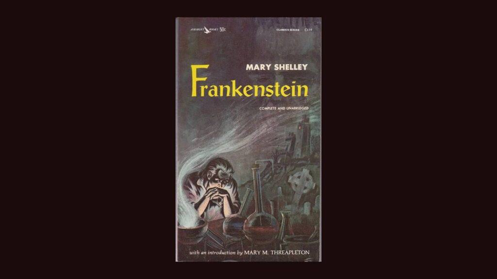 An image of a book cover for the novel FRANKENSTEIN, of a man seated at a table, surrounded by chemistry equipment